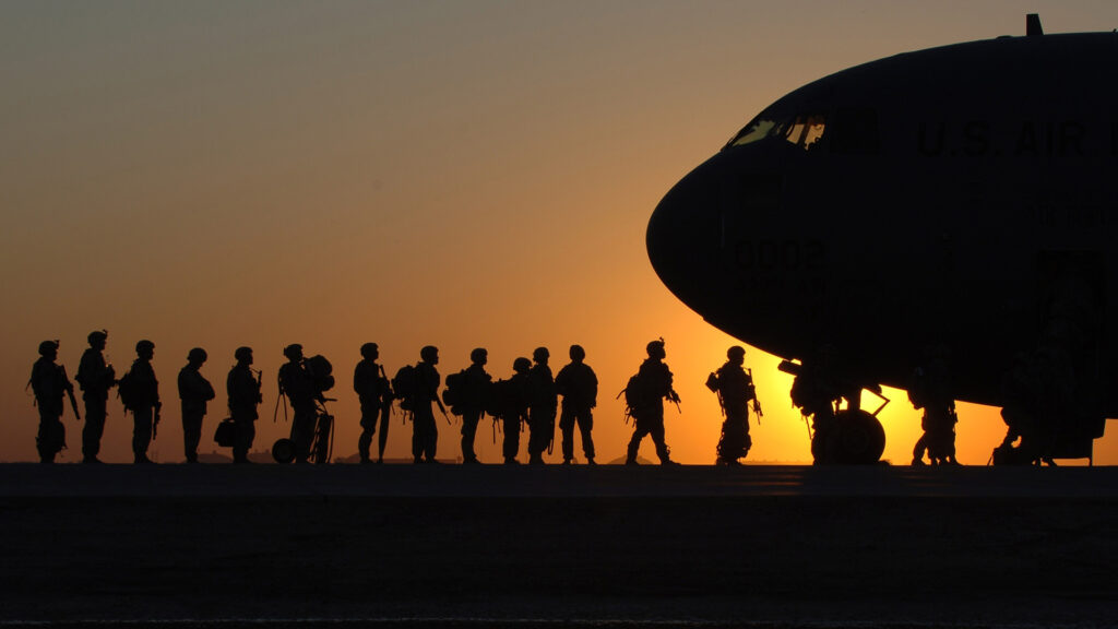 Members of the United States military boarding a plane at sunset
